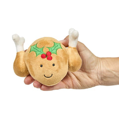 Plush toy resembling a roasted turkey with a face and holly decoration held in a hand 